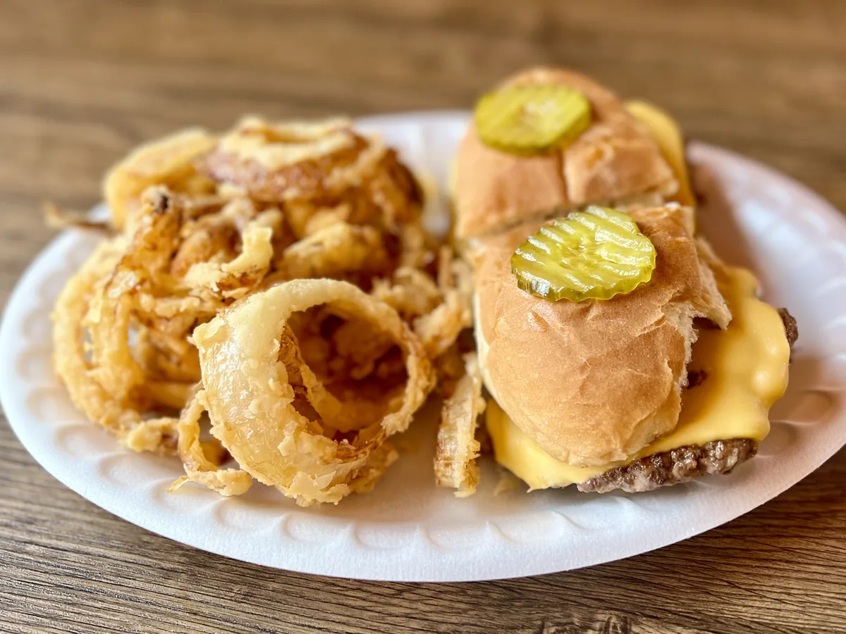 Cheeseburger sliders served with a plate of hand-breaded onion rings