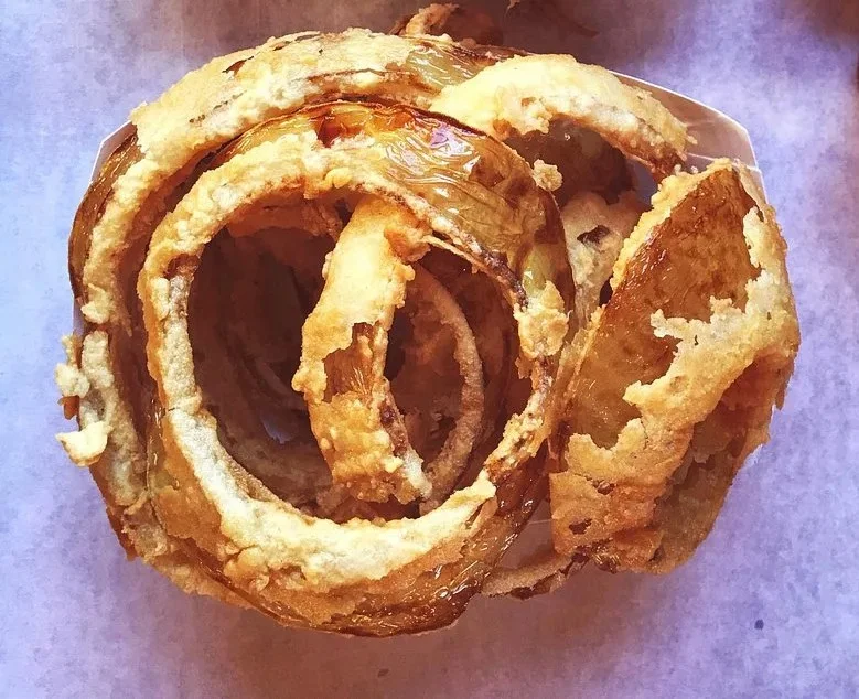 Close-up of a basket of hand-breaded onion rings