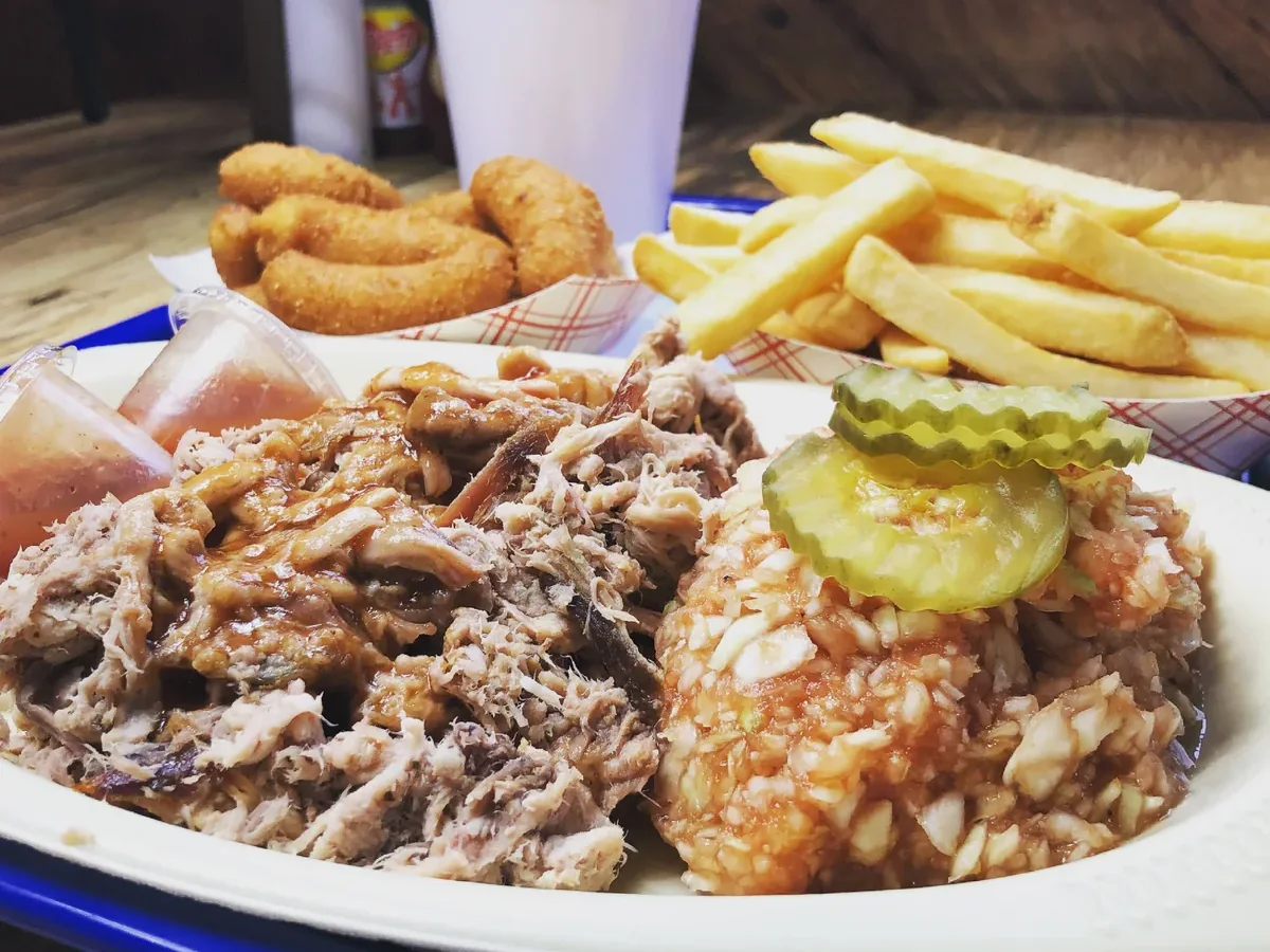 BBQ plate with chopped pit-smoked pork, red slaw and pickles, hushpuppies, fries, and sauce cups